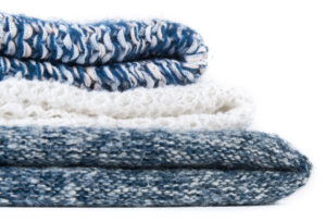 Wool socks and stack of various sweaters. Winter style. Isolated on white