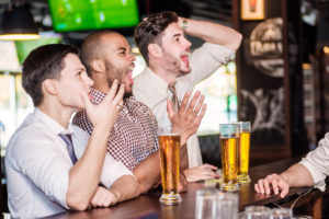 Men fans watching football on TV and drink beer. Three other men